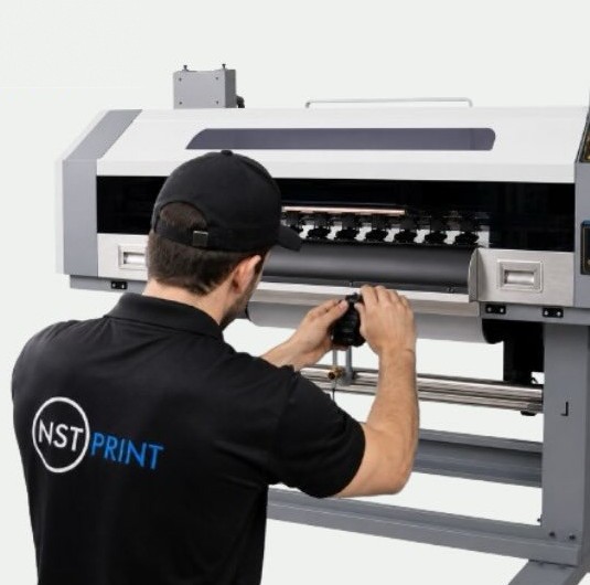 Técnico da NST Print de camisa preta ajustando o cabeçote de uma impressora DTF